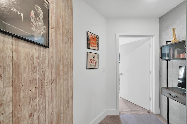 hall with light carpet and wooden walls