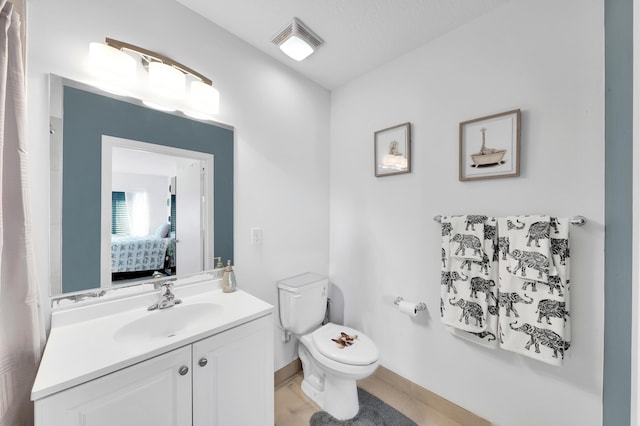 bathroom with a textured ceiling, toilet, vanity, and tile patterned flooring