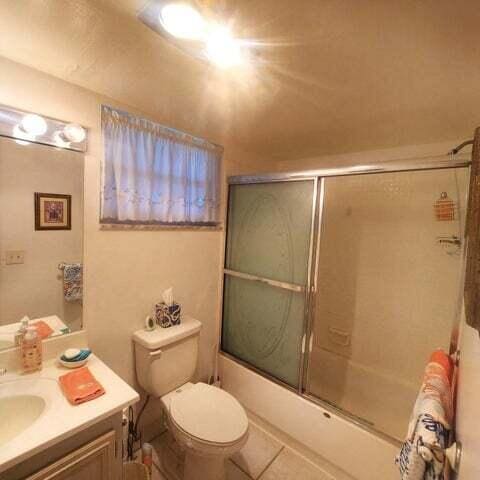 full bathroom with shower / bath combination with glass door, tile patterned floors, vanity, and toilet