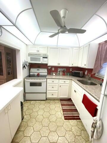 kitchen featuring ceiling fan, sink, white cabinets, and white appliances