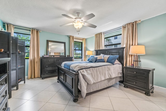 bedroom with ceiling fan, light tile patterned floors, and a textured ceiling