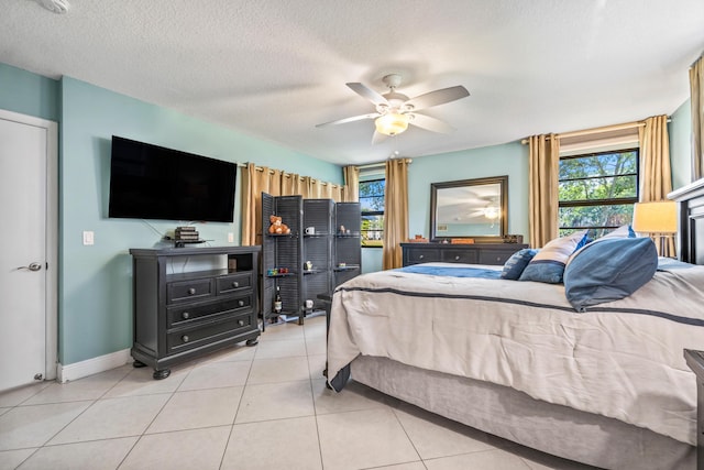 bedroom featuring ceiling fan, light tile patterned flooring, a textured ceiling, and a fireplace