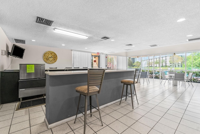 kitchen featuring a breakfast bar, a textured ceiling, and an island with sink