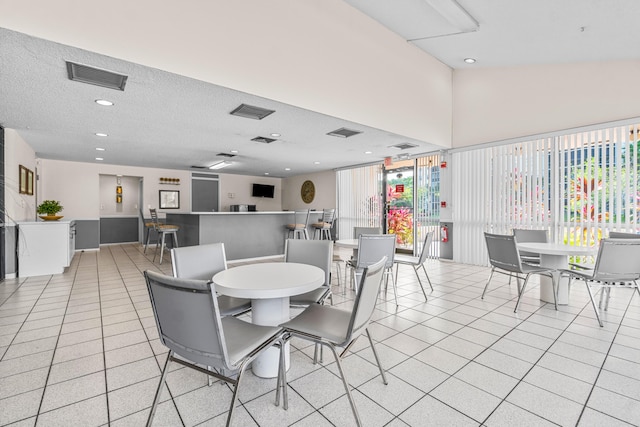 dining room featuring a textured ceiling, light tile patterned flooring, and lofted ceiling