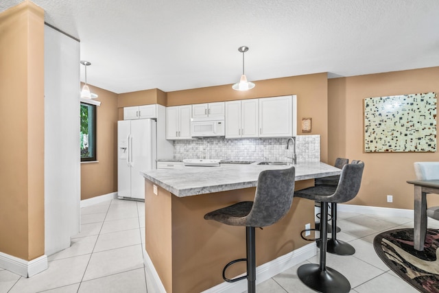 kitchen featuring decorative backsplash, white appliances, white cabinetry, and hanging light fixtures