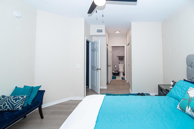 bedroom featuring hardwood / wood-style floors, ceiling fan, and ensuite bath