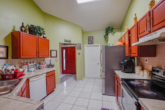 kitchen featuring light tile patterned floors, sink, appliances with stainless steel finishes, decorative backsplash, and vaulted ceiling