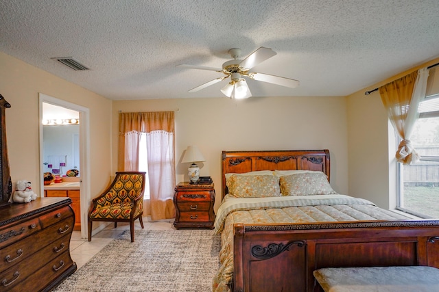 tiled bedroom featuring connected bathroom, a textured ceiling, and ceiling fan