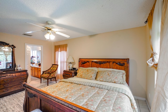 tiled bedroom with connected bathroom, a textured ceiling, and ceiling fan