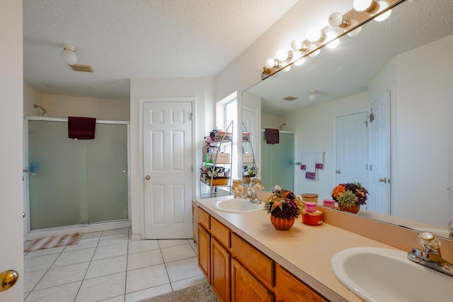 bathroom featuring tile patterned floors, a shower with shower door, vanity, and a textured ceiling