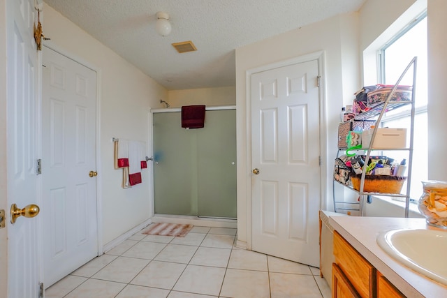 bathroom featuring tile patterned flooring, vanity, a textured ceiling, and a shower with shower door