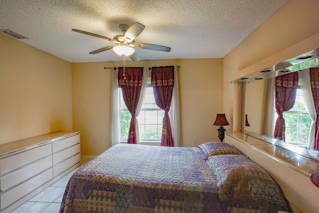 tiled bedroom with multiple windows, ceiling fan, and a textured ceiling