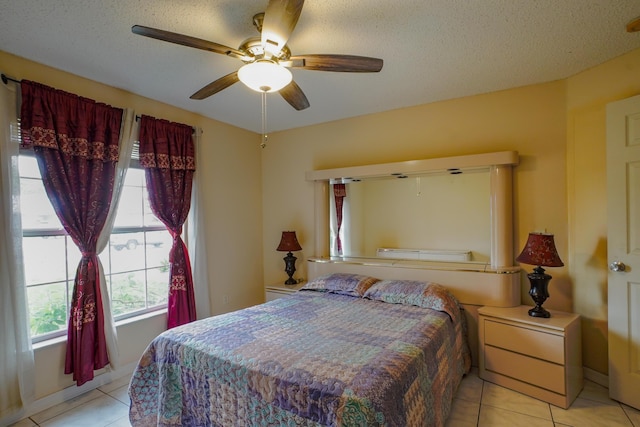 bedroom with ceiling fan, light tile patterned floors, and a textured ceiling