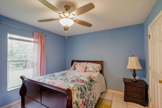 bedroom featuring ceiling fan, light tile patterned floors, and a textured ceiling