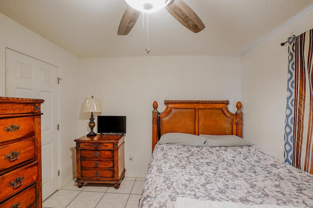 tiled bedroom with ceiling fan and a textured ceiling