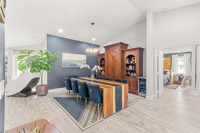 bar featuring light wood-type flooring, decorative light fixtures, an inviting chandelier, and high vaulted ceiling