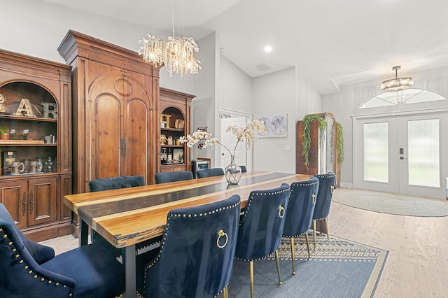 dining space featuring an inviting chandelier, french doors, vaulted ceiling, built in shelves, and light hardwood / wood-style floors