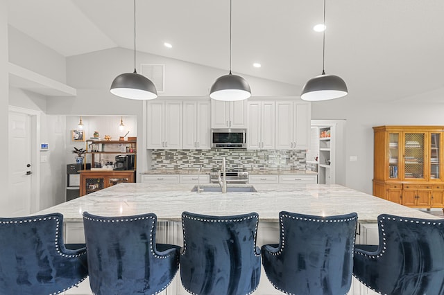 kitchen featuring sink, tasteful backsplash, lofted ceiling, decorative light fixtures, and white cabinets