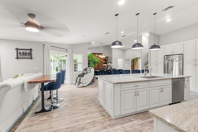 kitchen with white cabinetry, sink, hanging light fixtures, and stainless steel appliances