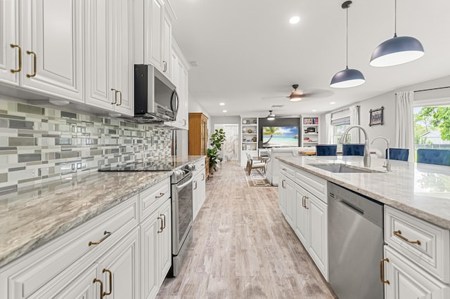 kitchen featuring pendant lighting, sink, light stone counters, white cabinetry, and stainless steel appliances