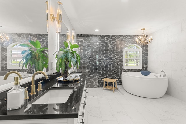 bathroom with a notable chandelier, a bathtub, sink, and tile walls