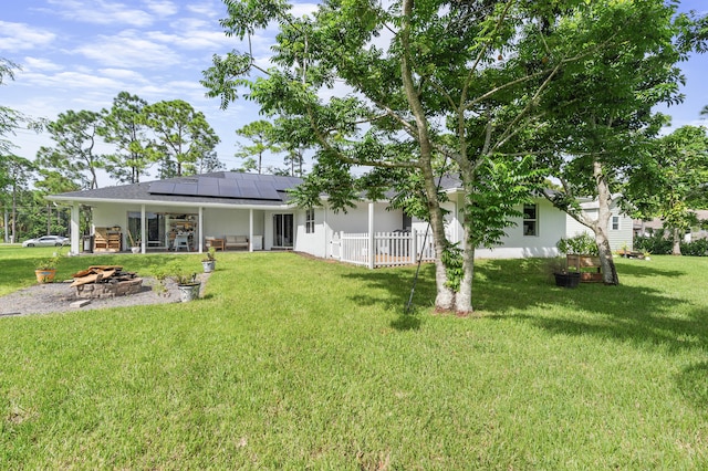 back of property with solar panels and a yard