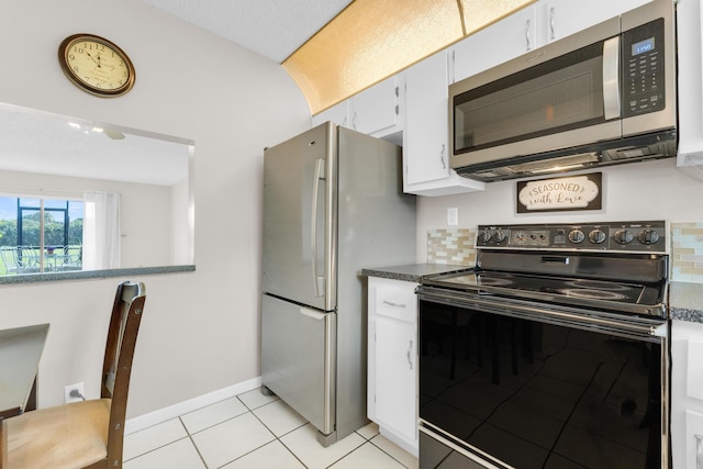 kitchen with tasteful backsplash, appliances with stainless steel finishes, light tile patterned floors, and white cabinets