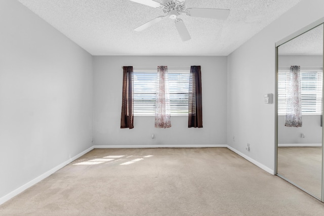 carpeted spare room with ceiling fan, a healthy amount of sunlight, and a textured ceiling