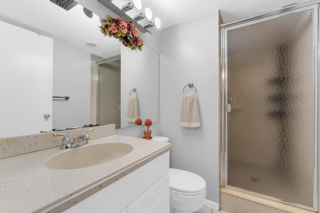 bathroom featuring vanity, a shower with door, and toilet