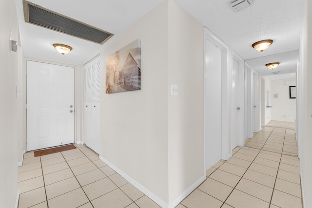 hallway featuring a textured ceiling and light tile patterned floors