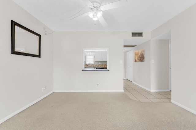 empty room with light carpet, ceiling fan, sink, and a textured ceiling