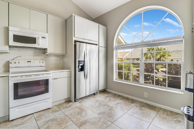 kitchen with lofted ceiling, white cabinetry, plenty of natural light, and white appliances