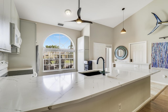 kitchen with light stone counters, sink, hanging light fixtures, and stove