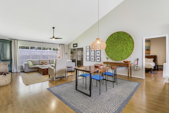 dining area with hardwood / wood-style floors, high vaulted ceiling, and ceiling fan