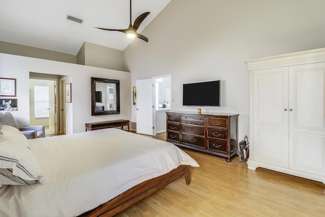 bedroom with high vaulted ceiling, ceiling fan, connected bathroom, light hardwood / wood-style floors, and a closet