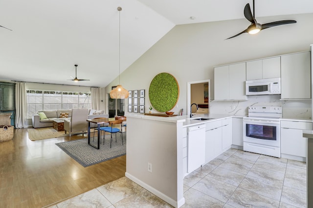 kitchen with white appliances, white cabinets, sink, hanging light fixtures, and kitchen peninsula