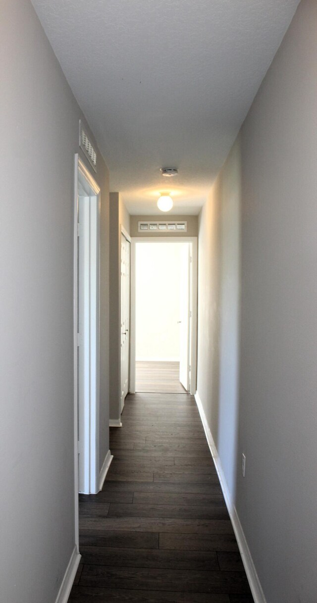 corridor featuring dark wood-style floors and baseboards