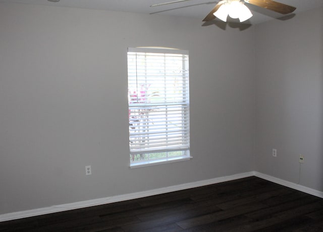 empty room featuring dark wood-type flooring, a ceiling fan, and baseboards