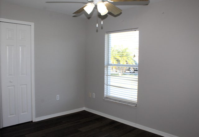 unfurnished room featuring a healthy amount of sunlight, baseboards, dark wood finished floors, and a ceiling fan