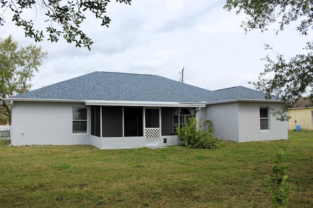 back of house with a yard, a shingled roof, a sunroom, and stucco siding