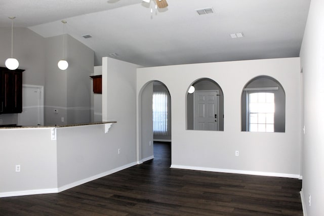 empty room with dark wood-style floors, lofted ceiling, visible vents, and a ceiling fan