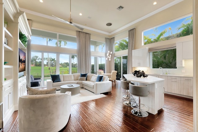 living room featuring a high ceiling, sink, ceiling fan, ornamental molding, and dark hardwood / wood-style flooring