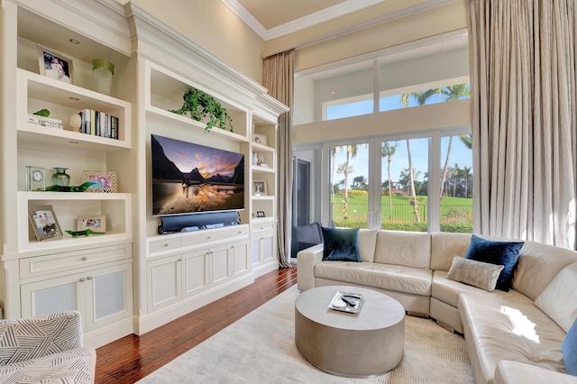 living room with built in shelves, crown molding, and wood-type flooring