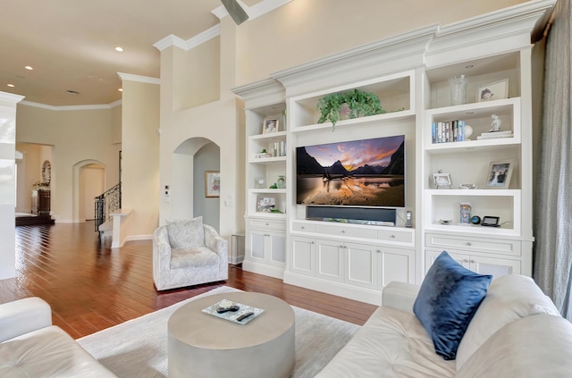 living room with built in shelves, light wood-type flooring, ornamental molding, and a high ceiling