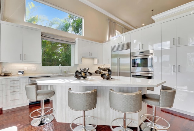 kitchen with a kitchen bar, appliances with stainless steel finishes, white cabinetry, and a high ceiling