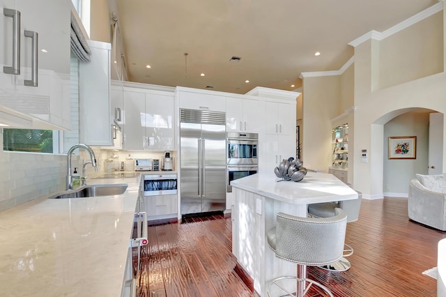 kitchen featuring sink, stainless steel appliances, tasteful backsplash, dark hardwood / wood-style flooring, and white cabinets