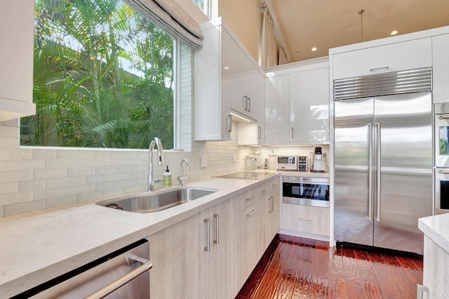 kitchen featuring appliances with stainless steel finishes, dark hardwood / wood-style flooring, tasteful backsplash, sink, and white cabinets