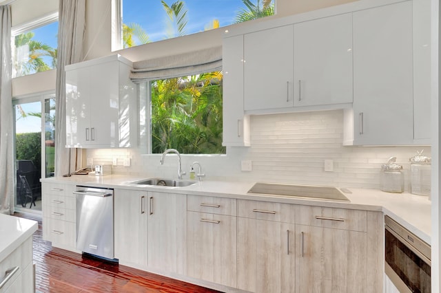 kitchen featuring decorative backsplash, sink, white cabinets, and black electric stovetop