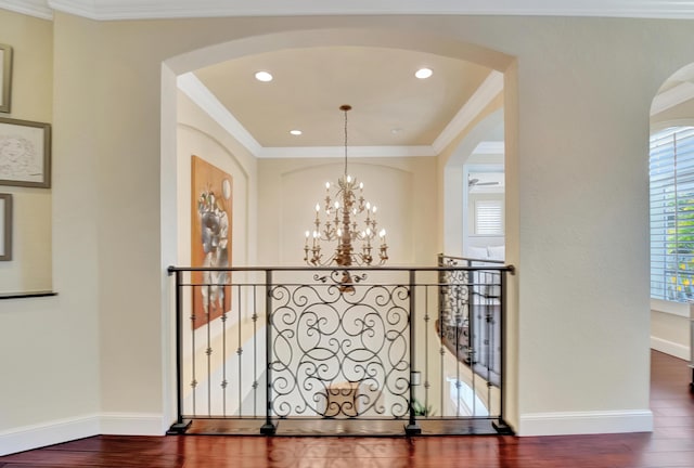 hallway with hardwood / wood-style floors, crown molding, and a chandelier