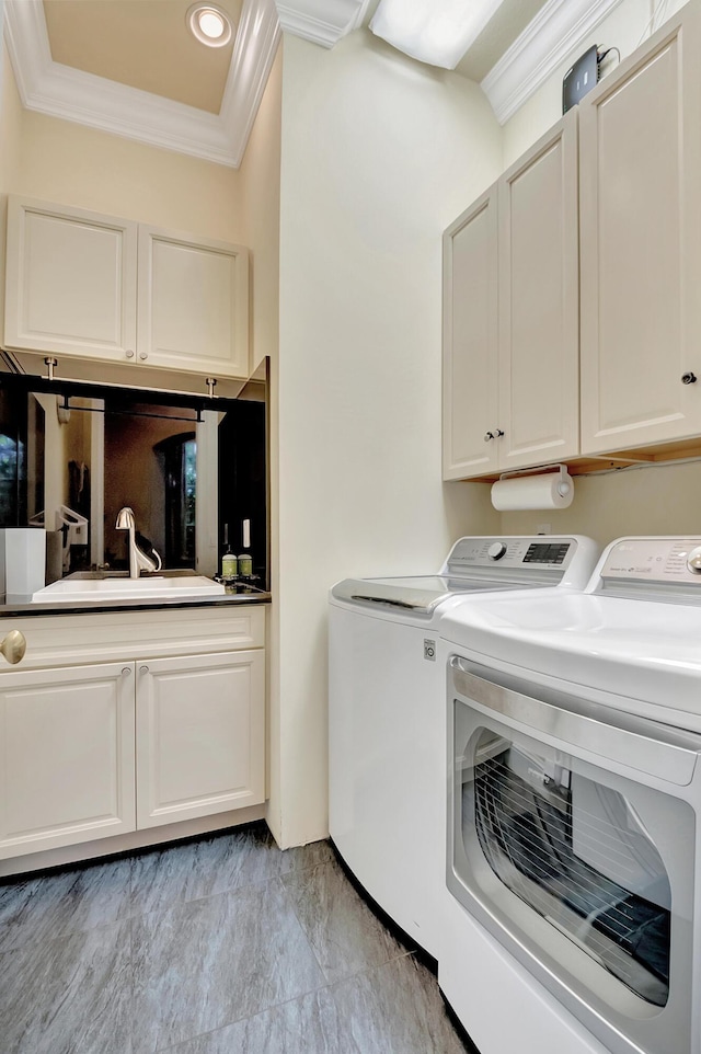 clothes washing area featuring cabinets, washer and clothes dryer, crown molding, and sink